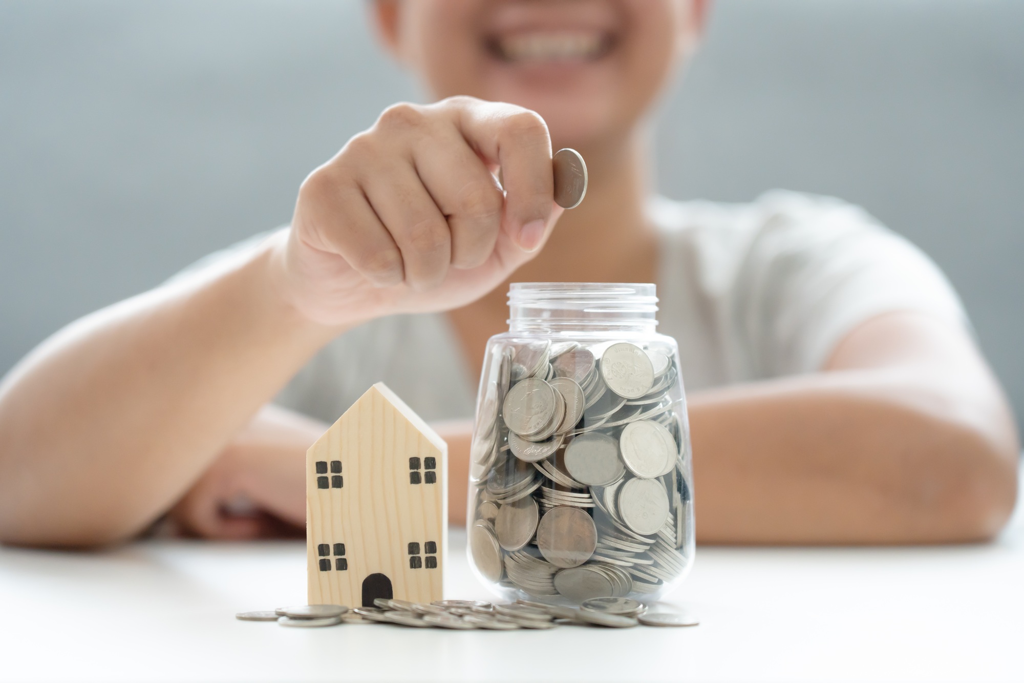 Woman savings money in coin jar for new property investment - Loan Select Australia Woman savings money in coin jar for new property investment