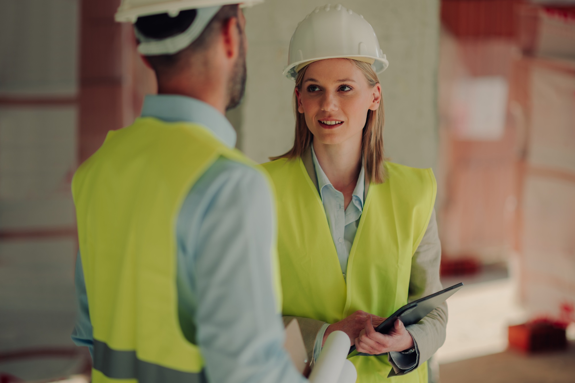 Engineers discussing building plans on construction site - Loan Select Australia Engineers discussing building plans on construction site